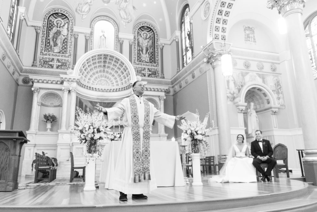 priest with open arms at st cecilia's boston addressing the guests with couple looking on