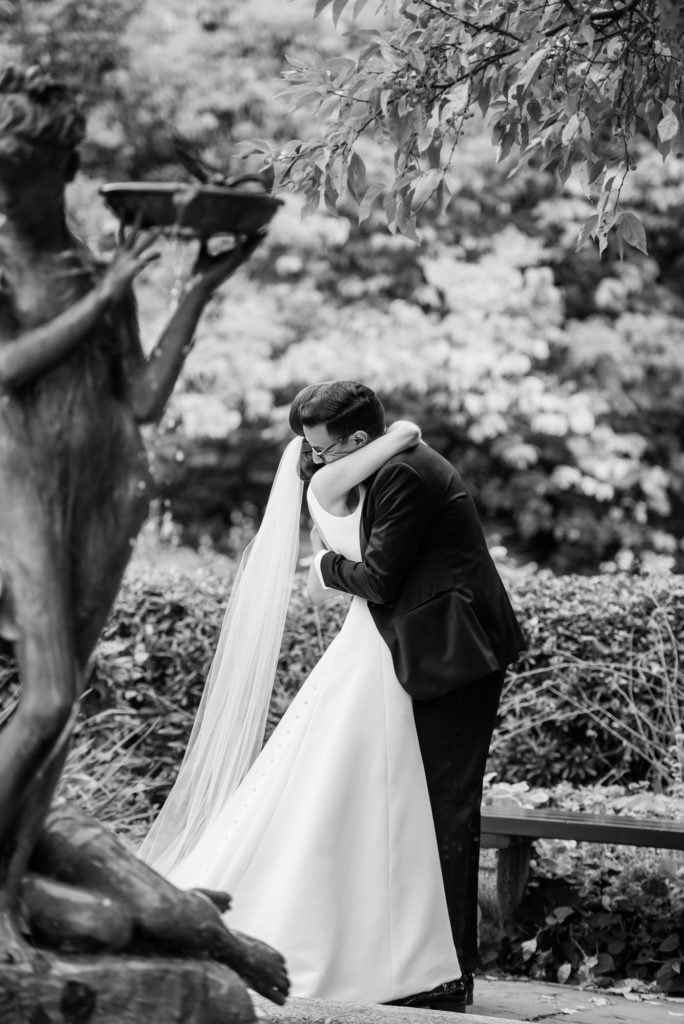 couple embrace during first look by fountain